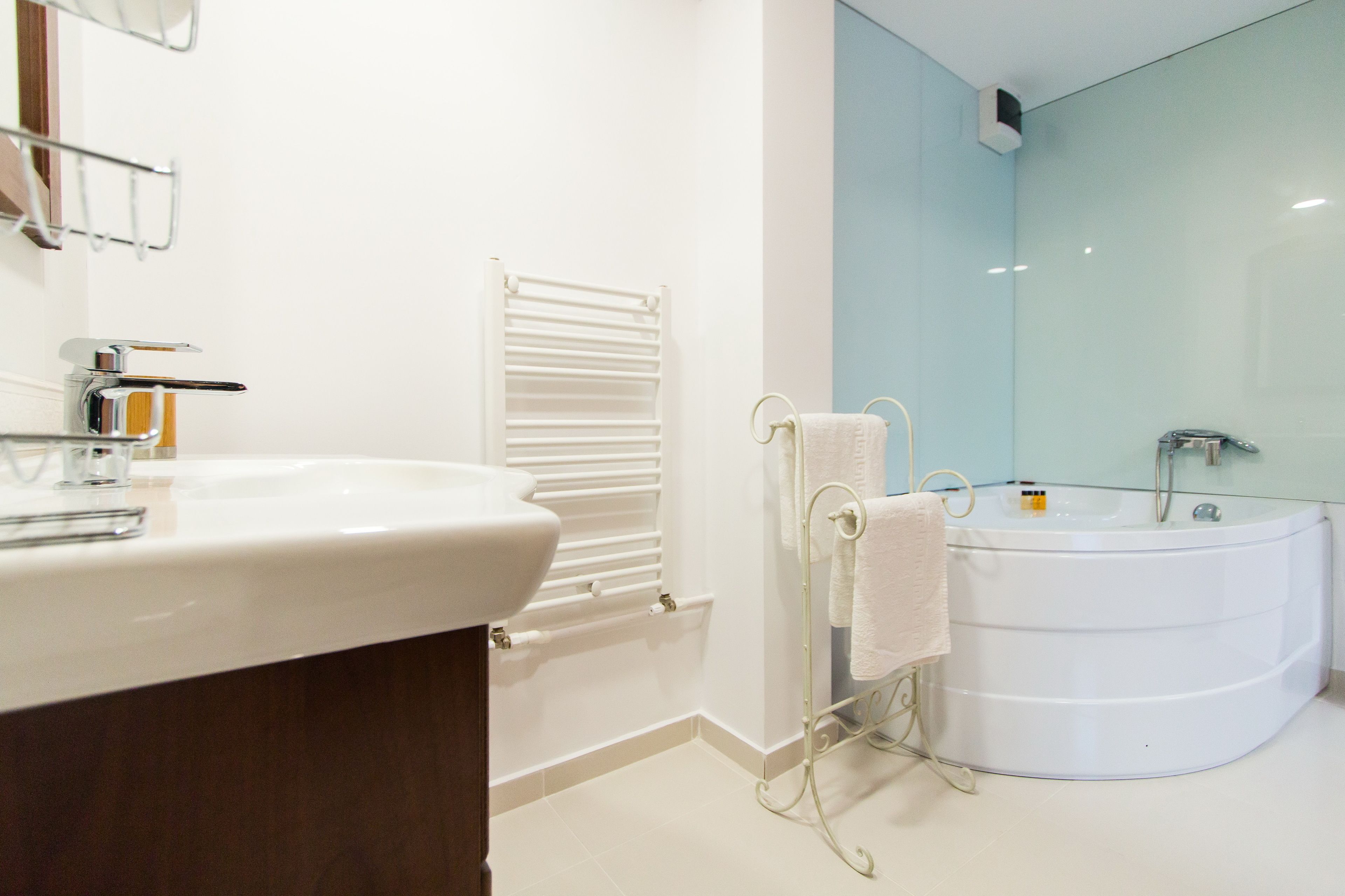 A modern bathroom with a white sink, a glass-enclosed bathtub, and a towel rack.