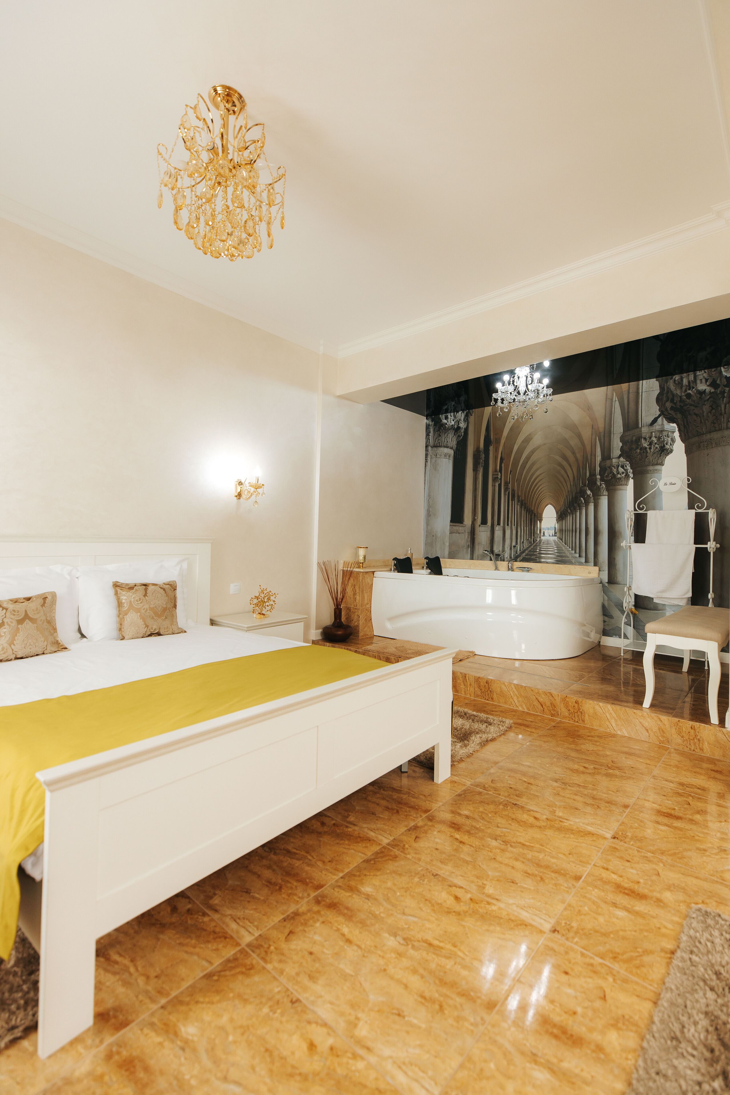 Un dormitorio moderno con una cama grande, una bañera y una araña.