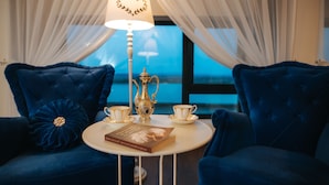 A room with a round table, two blue armchairs, a lamp, and a book. - Evianne Boutique Hotel (Galati)