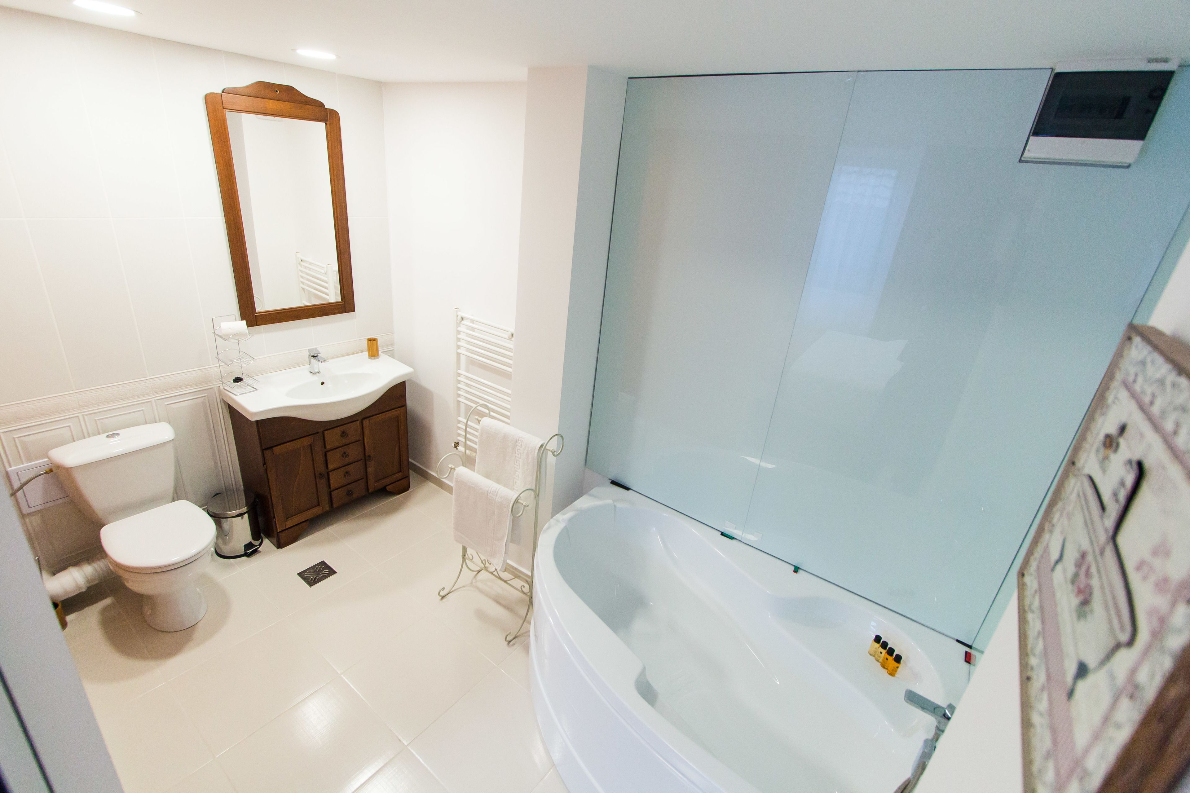 A bathroom with a toilet, sink, mirror, and bathtub.