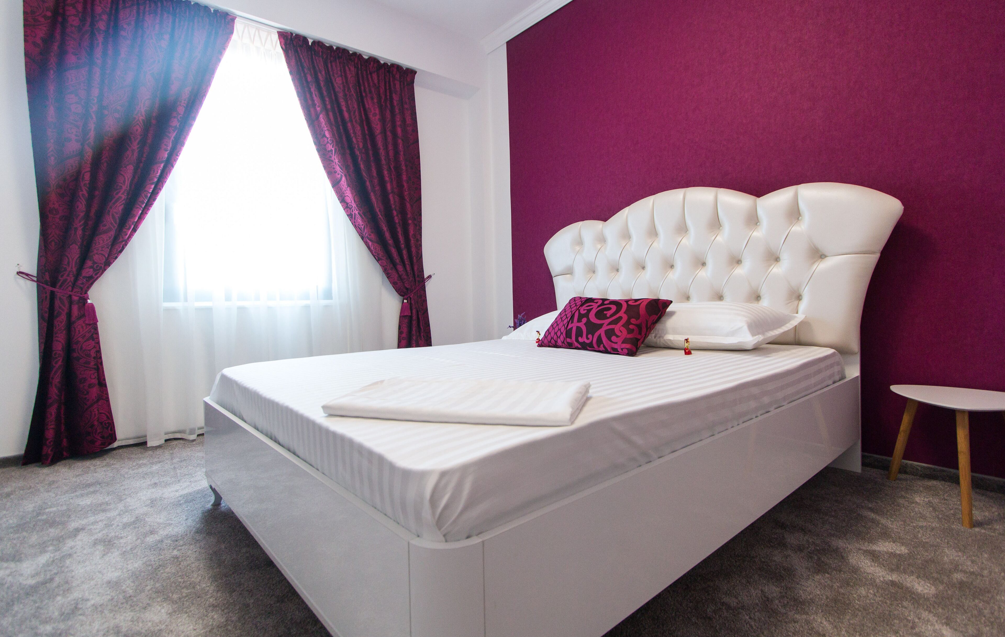 A modern bedroom with a large bed, a headboard, and a small side table.