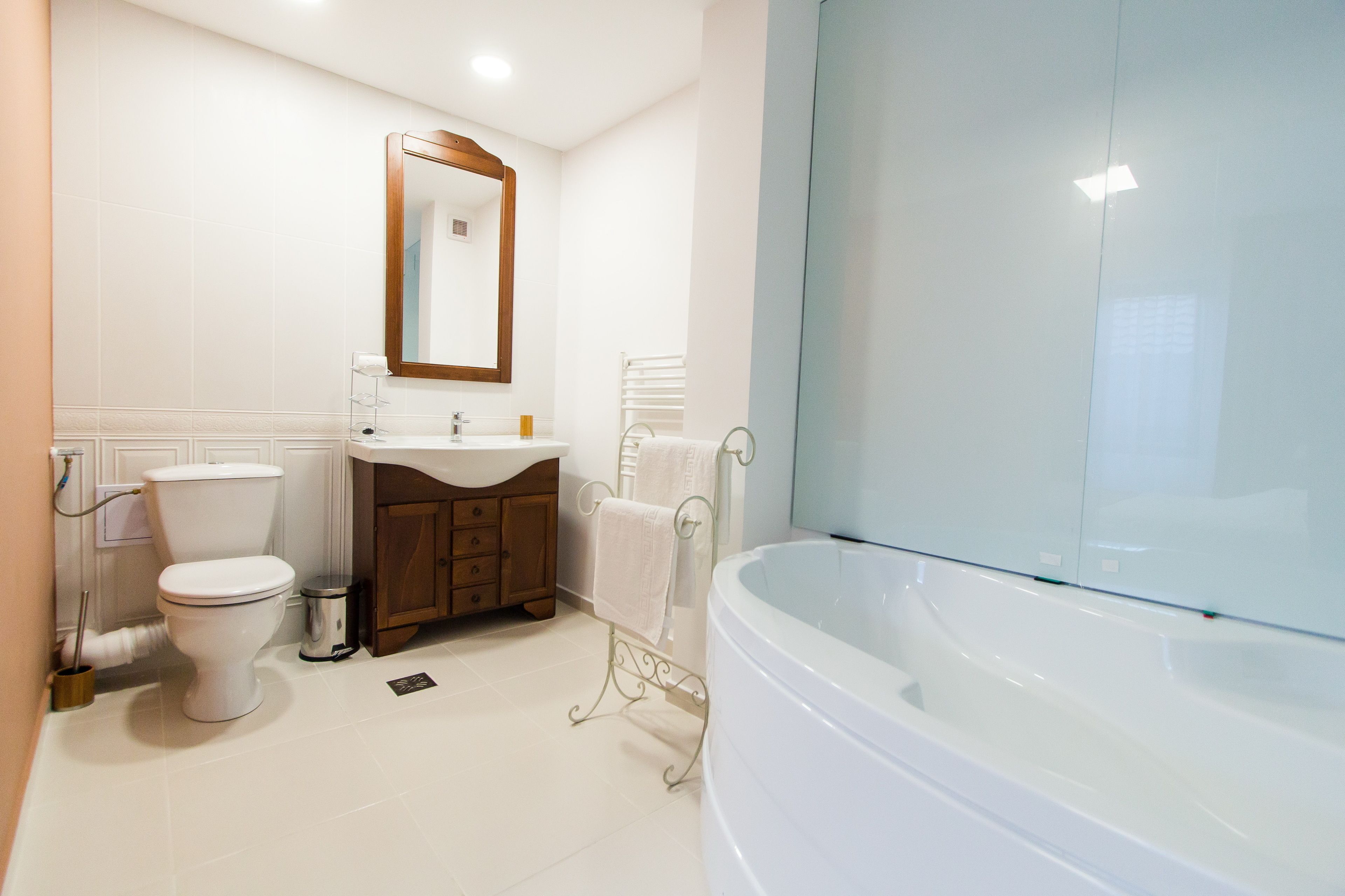 Een moderne badkamer met toilet, wastafel, badkamermeubel en bad.