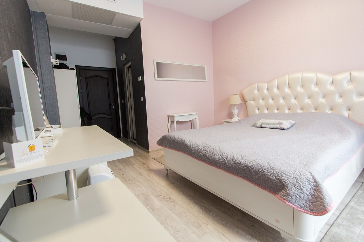Ein Schlafzimmer mit Bett, Nachttisch, Lampe und Schreibtisch inklusive Computer und Stuhl.