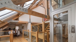 Een modern interieur met zichtbare houten balken, een glazen deur en een trap.