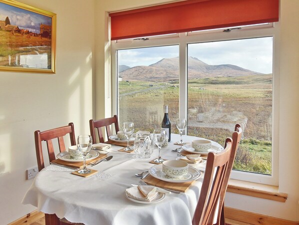 A dining table set for four with a scenic mountain view through a large window.
