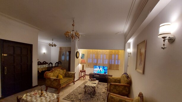 A living room with a sofa, chairs, a coffee table, a TV, and a chandelier. - Salem Apartment (Ismailia)