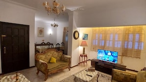 A living room with a sofa, a coffee table, a TV, and a chandelier. - Salem Apartment (Ismailia)