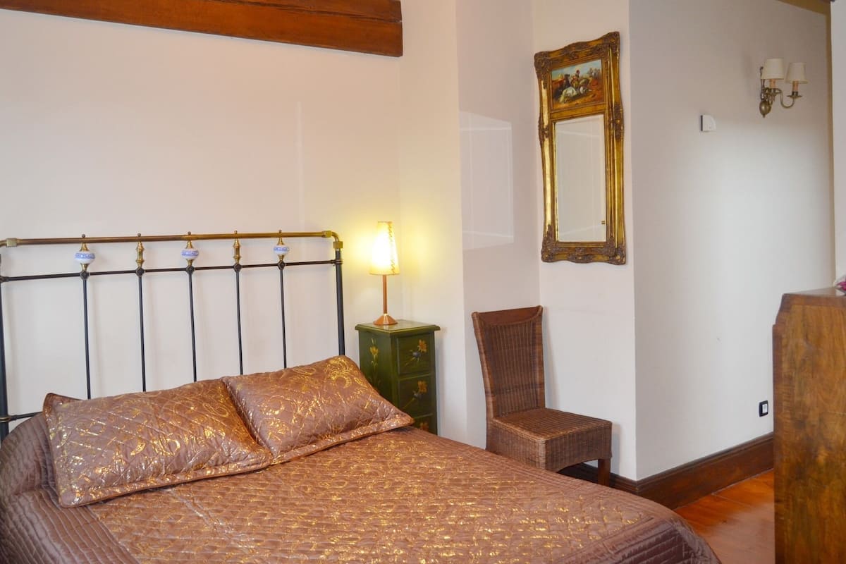 A bedroom with a bed, a nightstand, a chair, a mirror, and a lamp.