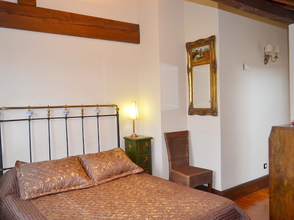 A bedroom with a bed, a nightstand, a chair, a mirror, and a lamp.