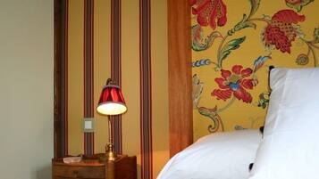 Une chambre à coucher avec un lit, une table de chevet, une lampe et un papier peint à motifs floraux.