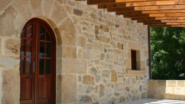 A stone building with a wooden door and a small window. - Posada el Hidalgo Mingucho (Medio Cudeyo)