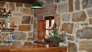 A bar area with stone walls, a wooden counter, and a basket of flowers. - Posada el Hidalgo Mingucho (Medio Cudeyo)