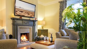 A cozy living room with a fireplace, comfortable seating, and a television mounted above it.
