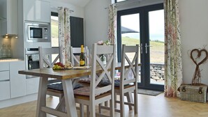 Une cuisine moderne avec des meubles blancs, un four à micro-ondes et un coin repas comprenant une table en bois et des chaises blanches.