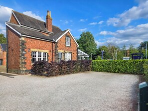 A brick house with a gravel driveway, a chimney, and a hedge. - 2 bedroom accommodation in Upper Poppleton, near York (Upper Poppleton, near York)