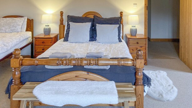 A bedroom with a wooden bed, two bedside tables with lamps, a wooden headboard, and a door leading to another room. - 5 bedroom accommodation in Bromyard, near Malvern Hills (Bromyard, near Malvern Hills)