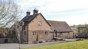 A stone farmhouse with two chimneys, a wooden staircase, and a gravel driveway. - 5 bedroom accommodation in Bromyard, near Malvern Hills (Bromyard, near Malvern Hills)