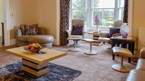 A living room with a sofa, armchairs, a coffee table, and a window with curtains. - Maesbangor Farmhouse (Capel Bangor, near Aberystwyth)