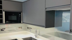 A modern kitchen with a built-in microwave, a stainless steel sink, and a sleek countertop design. - 1 bedroom accommodation in Whitby (Whitby)