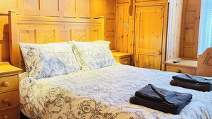A wooden-paneled bedroom with a bed, nightstands, and a dresser. - 1 bedroom accommodation in Whitby (Whitby)