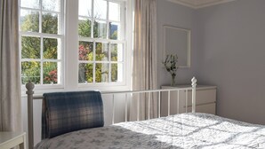 A bedroom with a bed, a window with curtains, a bedside table, and a dresser. - 3 bedroom accommodation in Fortingall, near Aberfeldy (Fortingall, near Aberfeldy)