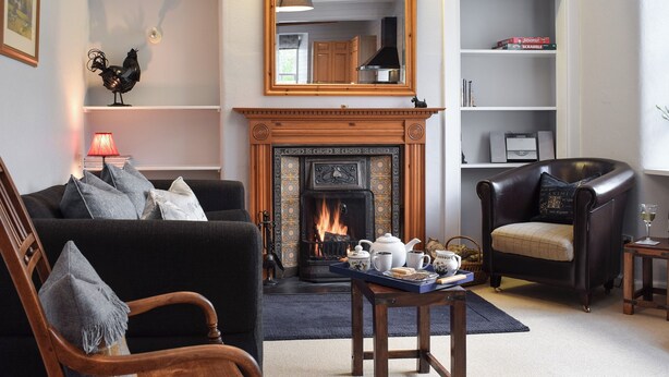 A cozy living room with a fireplace, a sofa, a chair, and a small table with tea set. - 3 bedroom accommodation in Fortingall, near Aberfeldy (Fortingall, near Aberfeldy)