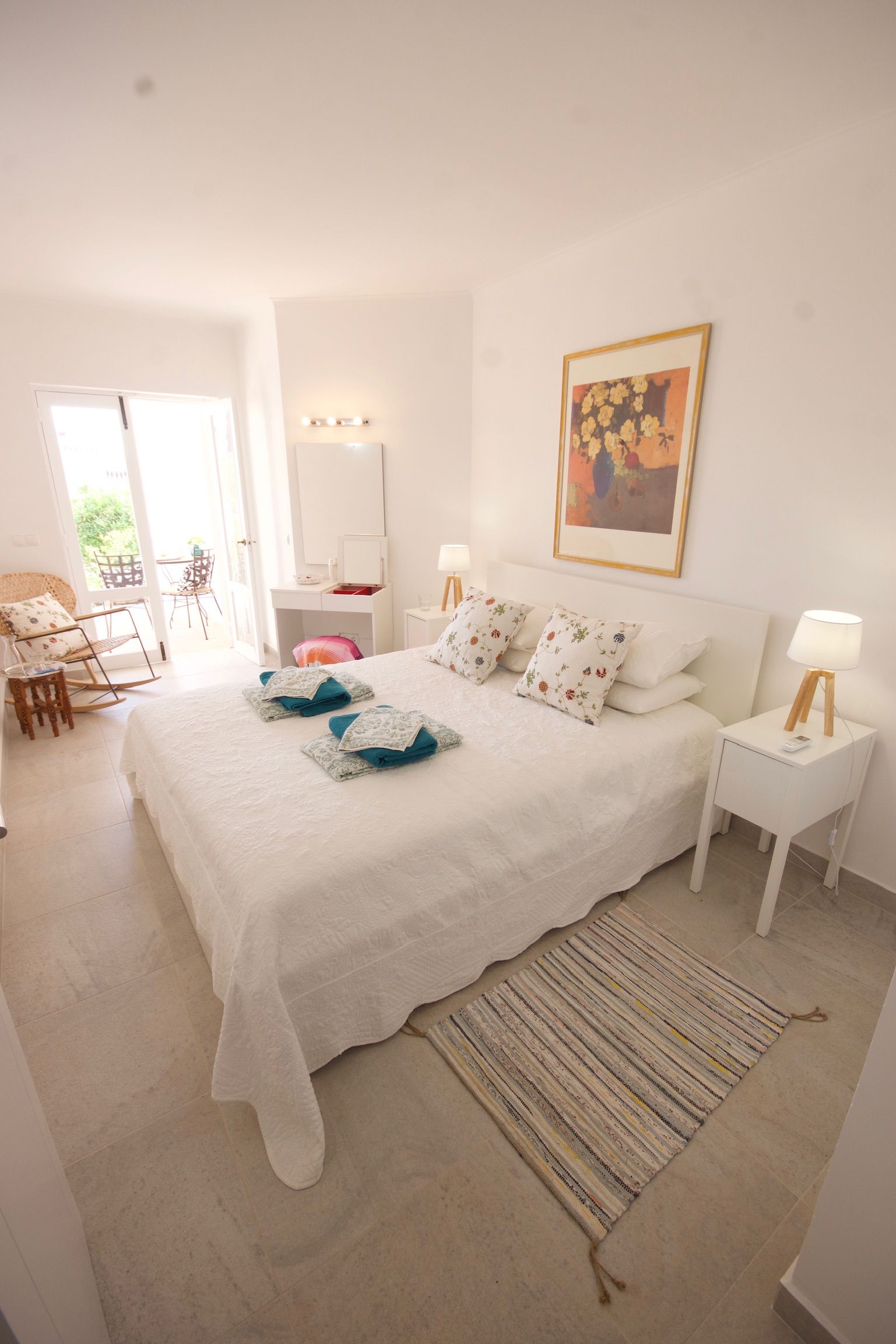 A bedroom with a large bed, two bedside tables, a chair, and a desk.
