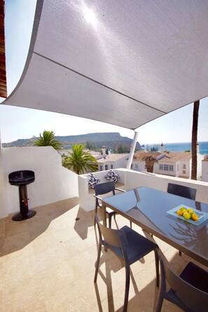 An outdoor patio with a table, chairs, and a grill.