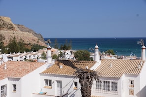 A coastal town with white buildings, a palm tree, and a view of the sea.