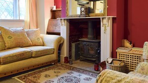 A cozy room with a sofa, a fireplace, a mirror, and a window with curtains. - 2 bedroom accommodation in Welton (Welton)