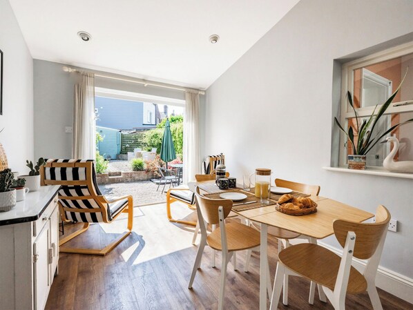 A dining area with a wooden table, chairs, and breakfast items.
