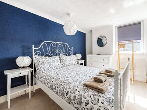 A bedroom with a bed, bedside tables, a dresser, a mirror, and a window with a view.
