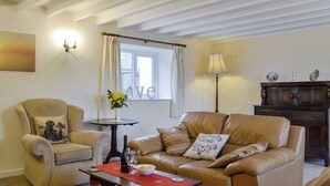 A living room with a sofa, armchair, and a small table with a vase and wine glasses. - 3 bedroom accommodation in Rhossilli, near Swansea (Rhossilli, near Swansea)