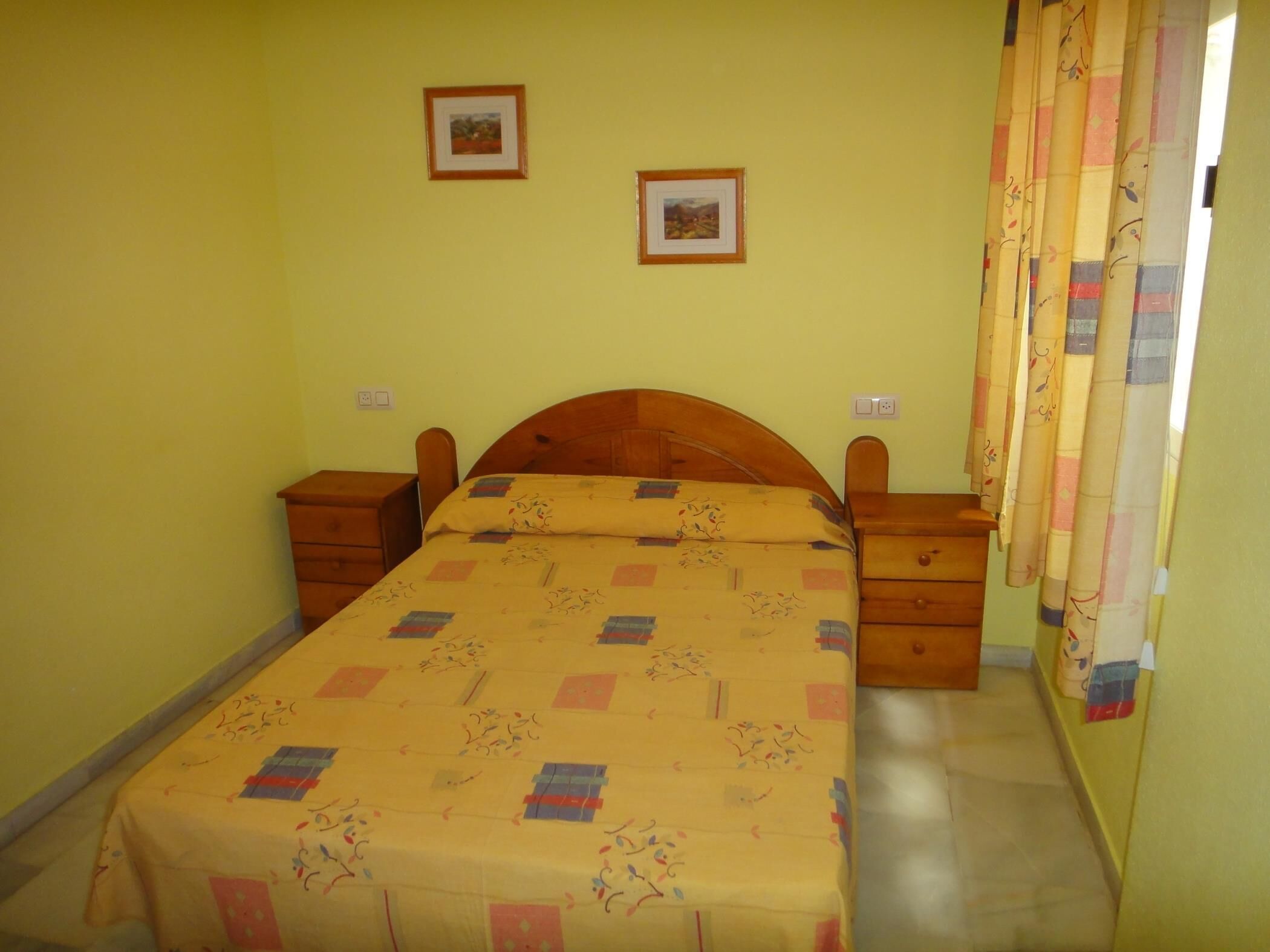 Ein Schlafzimmer mit einem hölzernen Bett, zwei Nachttischen und einem Vorhang.