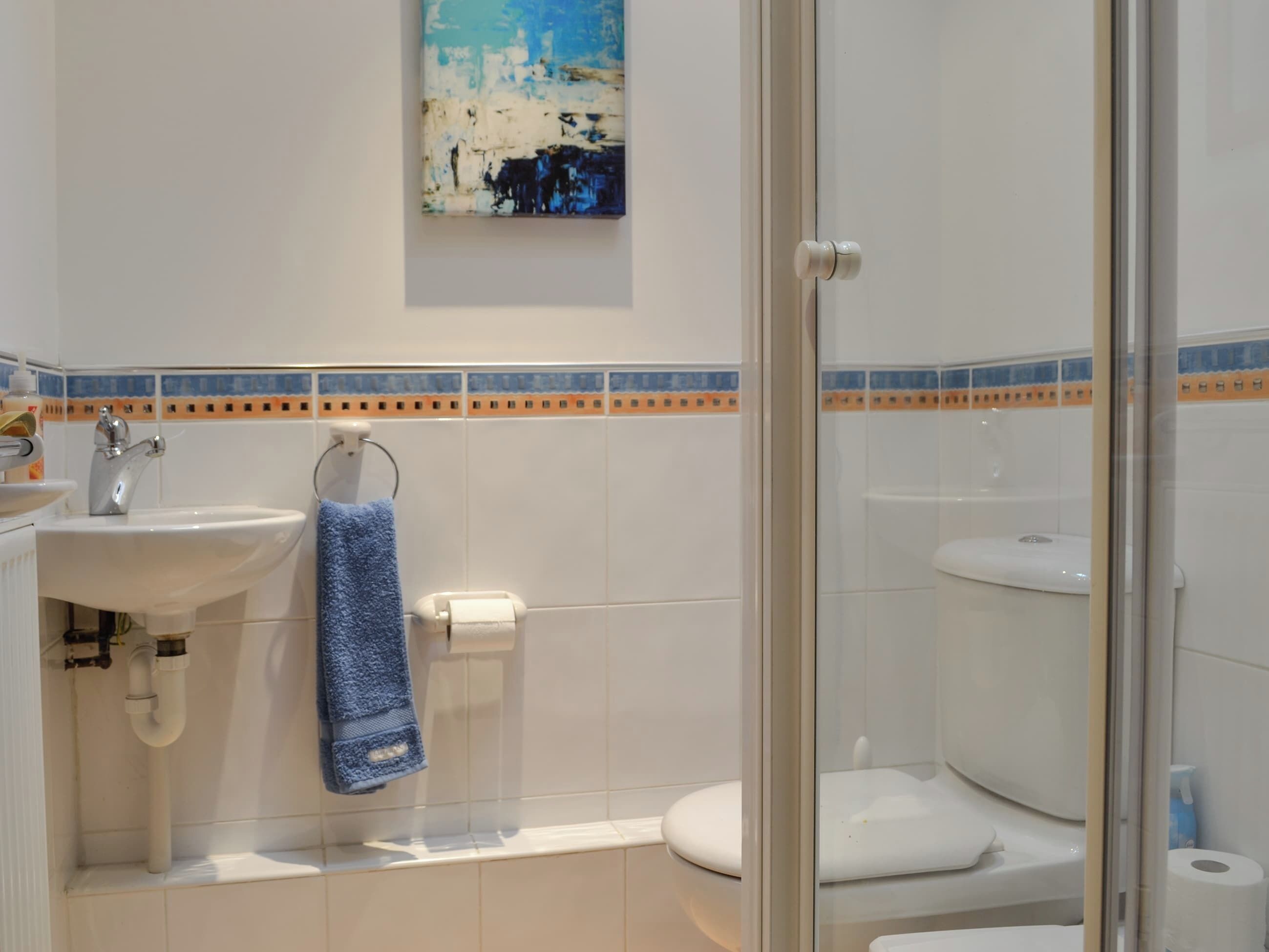 Un baño con lavamanos, inodoro y cabina de ducha de vidrio.