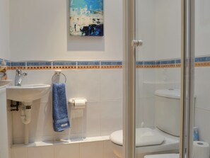 A bathroom with a sink, toilet, and glass shower enclosure.