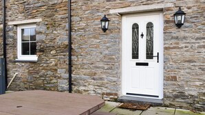 A stone building with a white door, two windows, and two wall-mounted lanterns. - 3 bedroom accommodation in Llangeitho, near Tregaron (Llangeitho, near Tregaron)