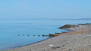 A rocky beach with a wooden jetty extending into calm waters. - 3 bedroom accommodation in Llangeitho, near Tregaron (Llangeitho, near Tregaron)