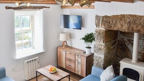 Un salon avec un mur en pierre, une cheminée, un téléviseur et un meuble en bois.