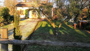 Una casa amb teulada de rajola, envoltada d'arbres i un pati amb gespa.