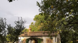 Una casa rústica amb teulada de rajola, envoltada d'un jardí ben cuidat amb taula de picnic i cadires blanques.