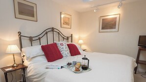 A neatly made bed with a tray of breakfast items, a lamp, and framed pictures on the walls. - 1 bedroom accommodation in Nether Wallop, near Stockbridge (Nether Wallop, near Stockbridge)