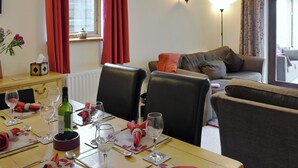 A dining area with a table set for two, a sofa, and a lamp. - 3 bedroom accommodation in Newbiggin on Lune, near Kirkby Stephen (Newbiggin on Lune, near Kirkby Stephen)
