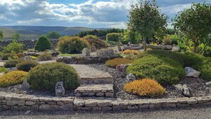 A garden with stone walls, various shrubs, and a stone pathway. - 3 bedroom accommodation in Newbiggin on Lune, near Kirkby Stephen (Newbiggin on Lune, near Kirkby Stephen)