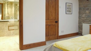 Quarto com porta de madeira, parede de pedra e um quadro pendurado na parede.