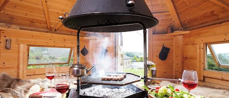A wooden interior with a grill, a bowl of salad, and a fur-covered couch.