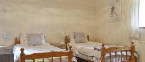 A room with two wooden beds, white walls, a radiator, and a poster of the Eiffel Tower.