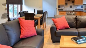 Una sala de estar moderna con sofás de cuero, una mesa de comedor y una cocina con gabinetes de madera y horno empotrado.