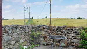 Eine Steinsäule mit einem Metalltisch und Blumen in einem Garten.