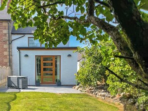 A house with a white exterior, a wooden front door, and a paved driveway leading to a grassy lawn. - 1 bedroom accommodation in Wiggonby, near Carlisle (Wiggonby, near Carlisle)